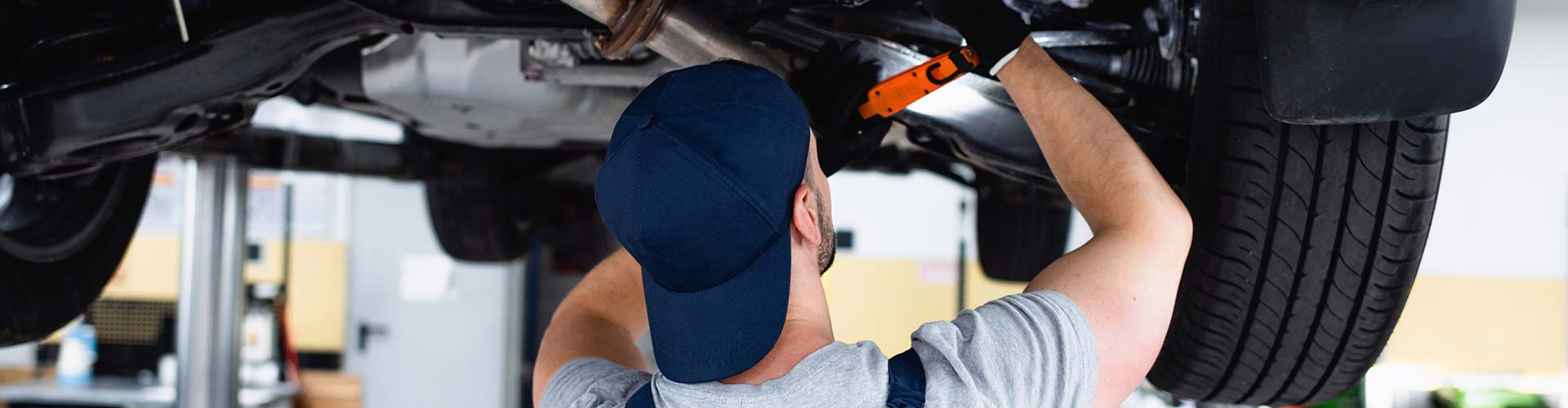 Mechanic working on the undercarriage of a car, showcasing detailed automotive repair in San Antonio, TX.